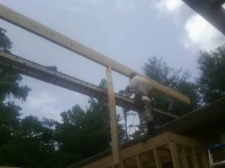 Carpenter setting a ridge beam over a new addition frame — Ice Dam Removal by Roofing Brothers in Lavon