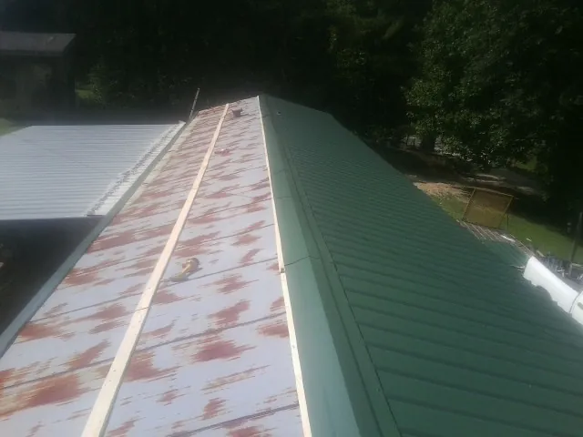 Old rusted panels beside newly installed green metal roofing — Wind Damage Roof Repair by Roofing Brothers in Lavon