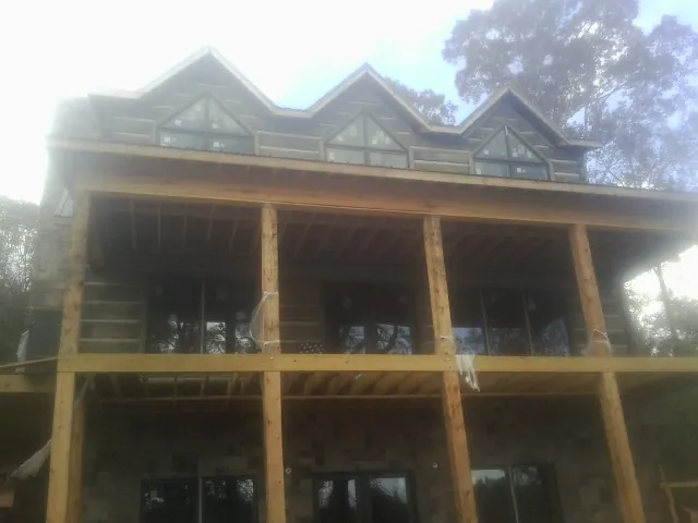 Dormers and porch framing on a large log home under construction — Roof Coating work by our crew in Lavon