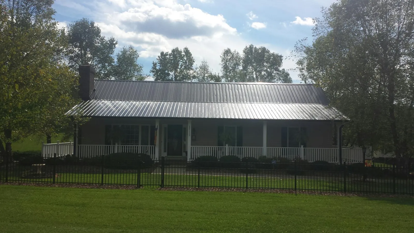 Gray metal roof on a brick ranch with a full width front porch — Gutter Guard Installation work by our crew in Lavon