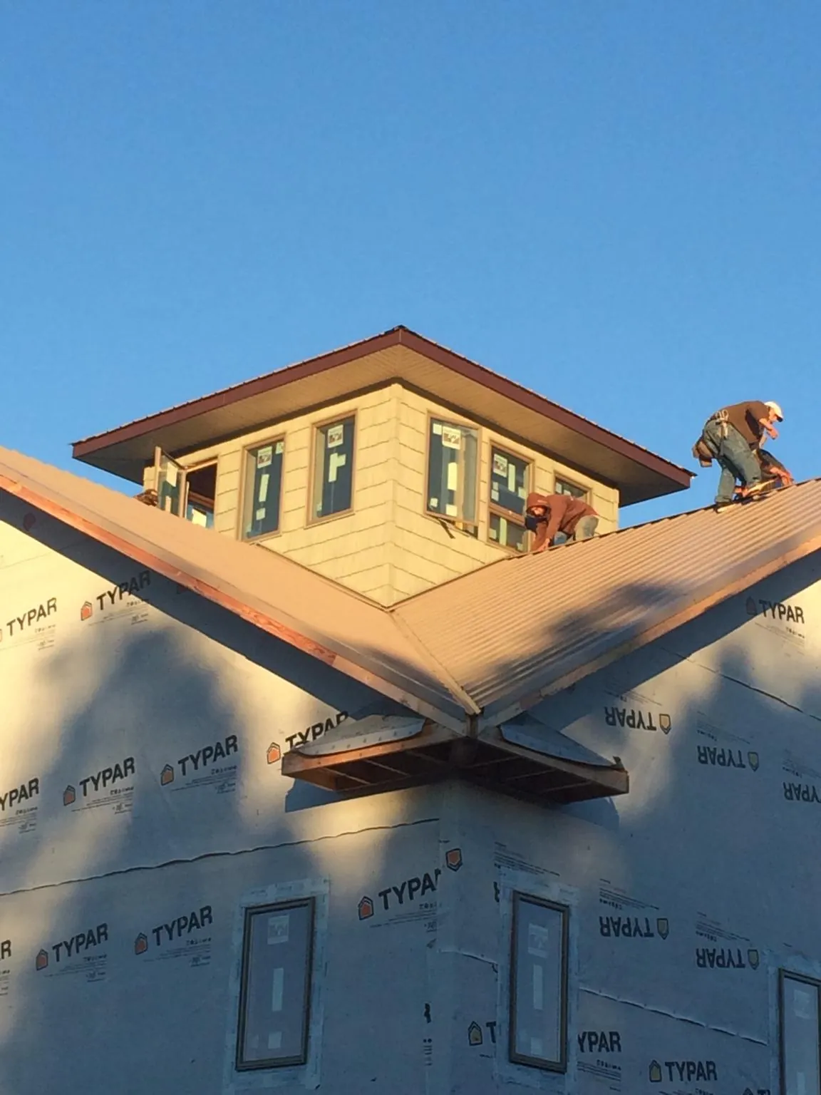 Roofers working around a rooftop cupola on a new metal roof at sunset — Roof Waterproofing in Lavon by Roofing Brothers